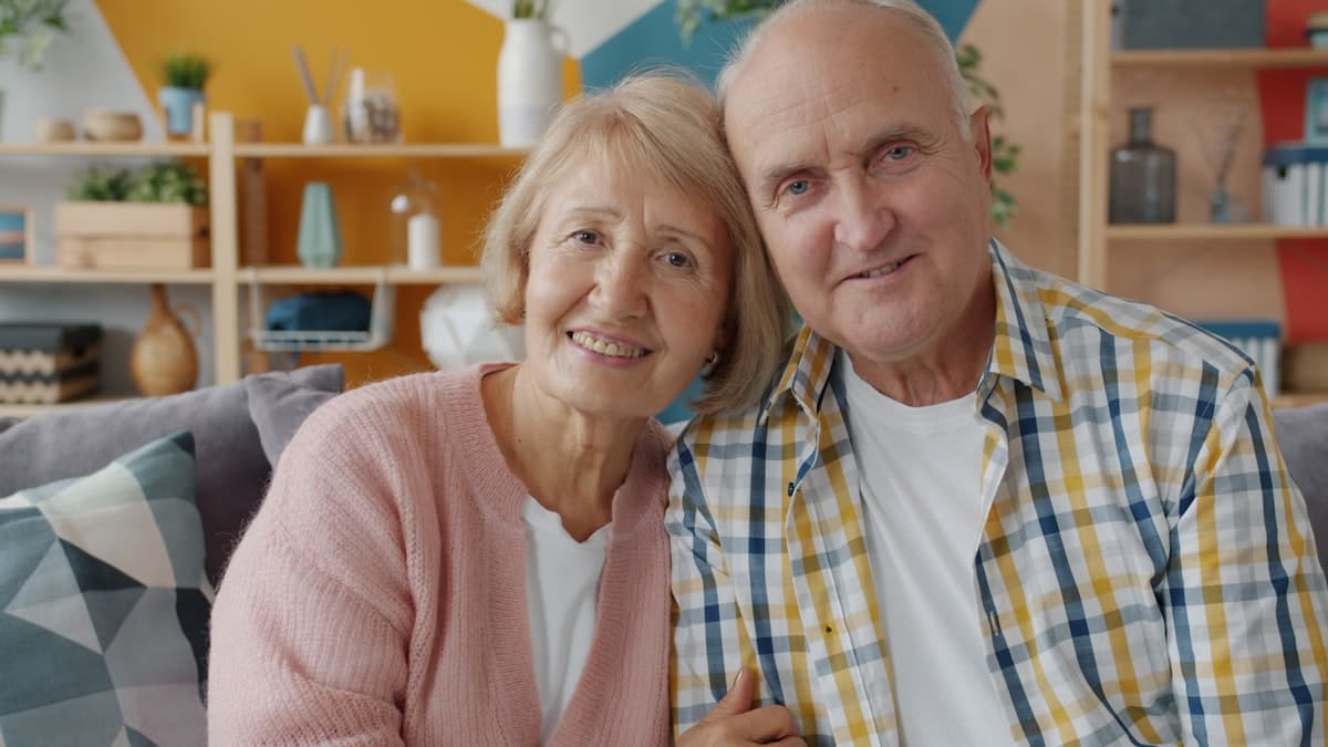 A couple in their seventies smiling on the couch