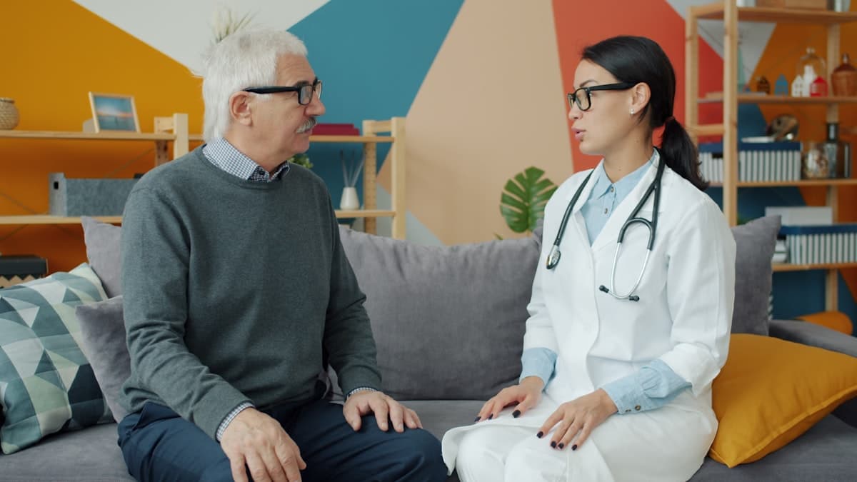 A doctor talking with an older man at home
